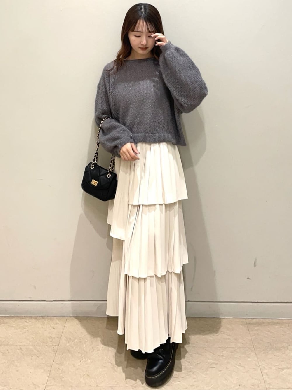 グレー系のニット/セーター、ホワイト系のスカート、ブラック系のショルダーバッグを着用したレディースの冬コーディネートの2枚目の写真