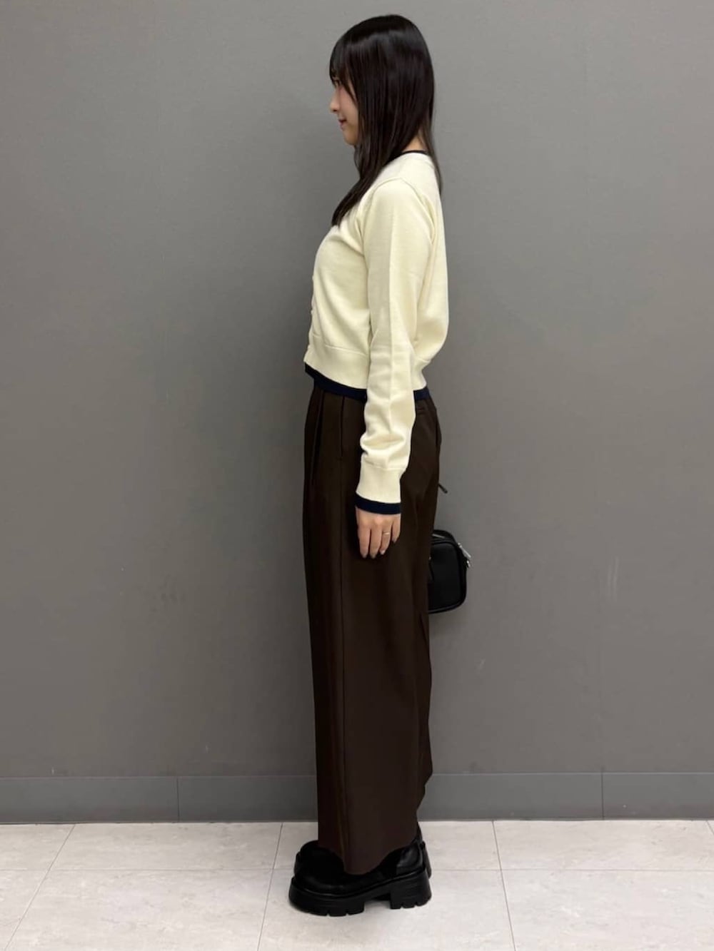ホワイト系のカーディガン/ボレロ、ブラウン系のスラックス、ブラック系のボストンバッグを着用したレディースの秋コーディネートの2枚目の写真
