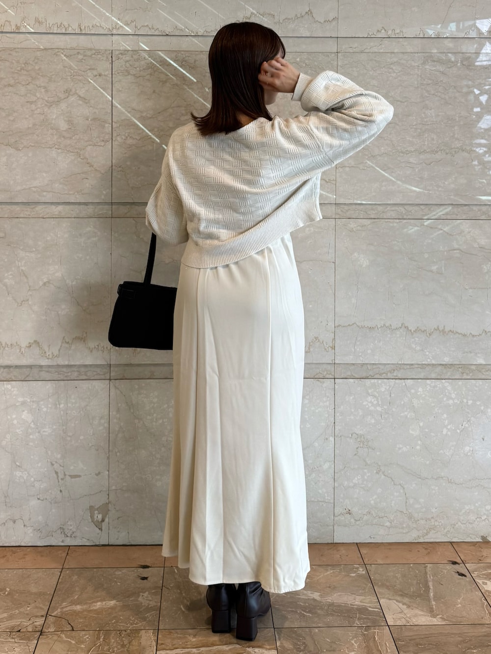 ホワイト系のワンピース、ブラック系のブーツ、ブラック系のショルダーバッグを着用したレディースの秋コーディネートの3枚目の写真