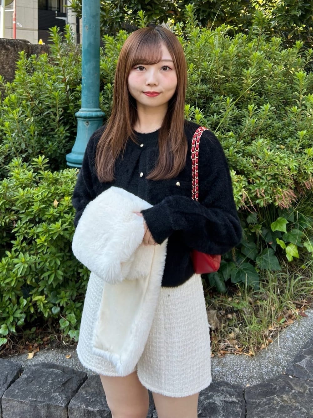 ホワイト系のその他パンツ、ブラック系のニット/セーター、レッド系のショルダーバッグを着用したレディースの冬コーディネートの2枚目の写真