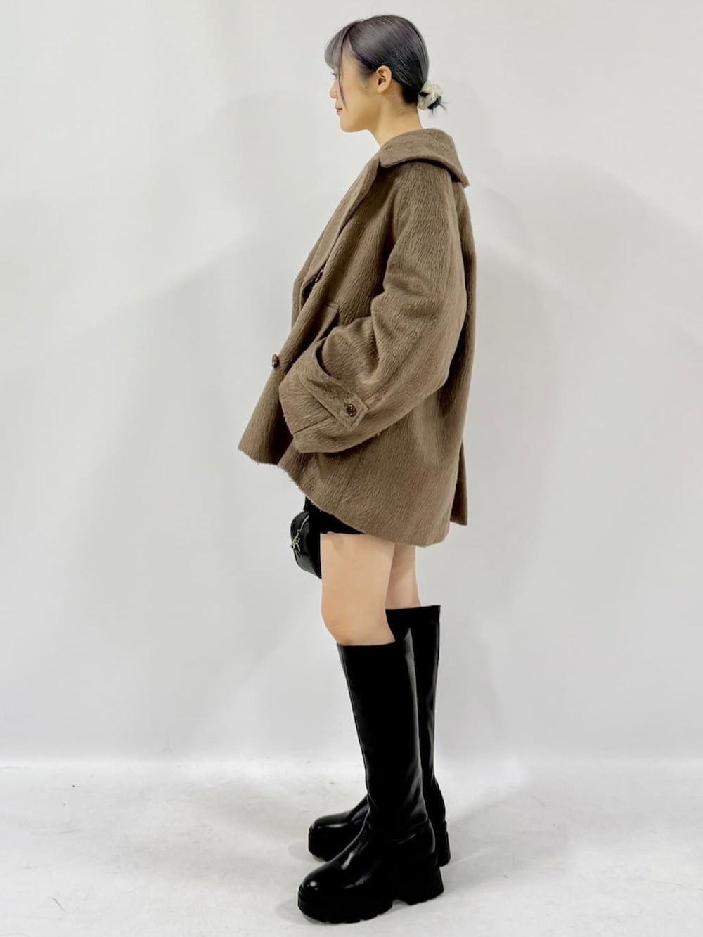 ブラック系のチェスターコート、ブラック系のスカート、ホワイト系のカーディガン/ボレロを着用したレディースの冬コーディネートの2枚目の写真