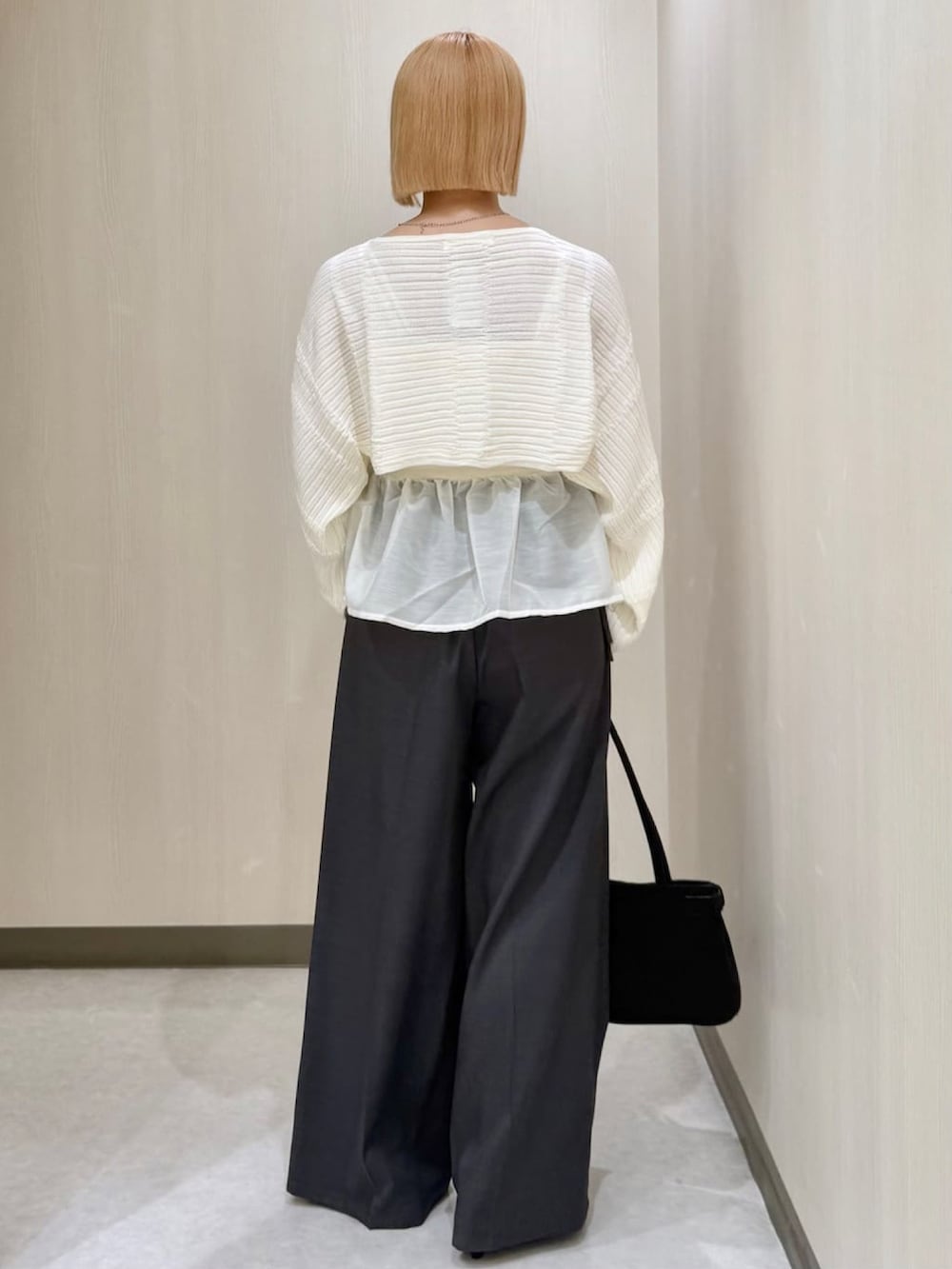 グレー系のスラックス、ブラック系のショルダーバッグ、ブラック系のパンプスを着用したレディースの秋コーディネートの3枚目の写真