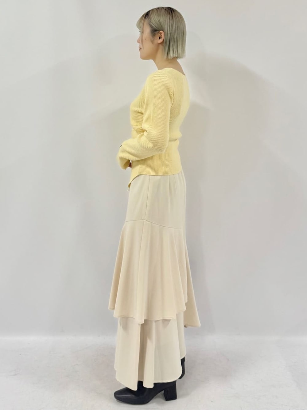 イエロー系のニット/セーター、ホワイト系のスカートを着用したレディースの冬コーディネートの2枚目の写真