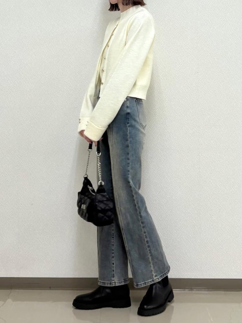 ホワイト系のアンサンブル、ブルー系のデニムパンツを着用したレディースの冬コーディネートの2枚目の写真