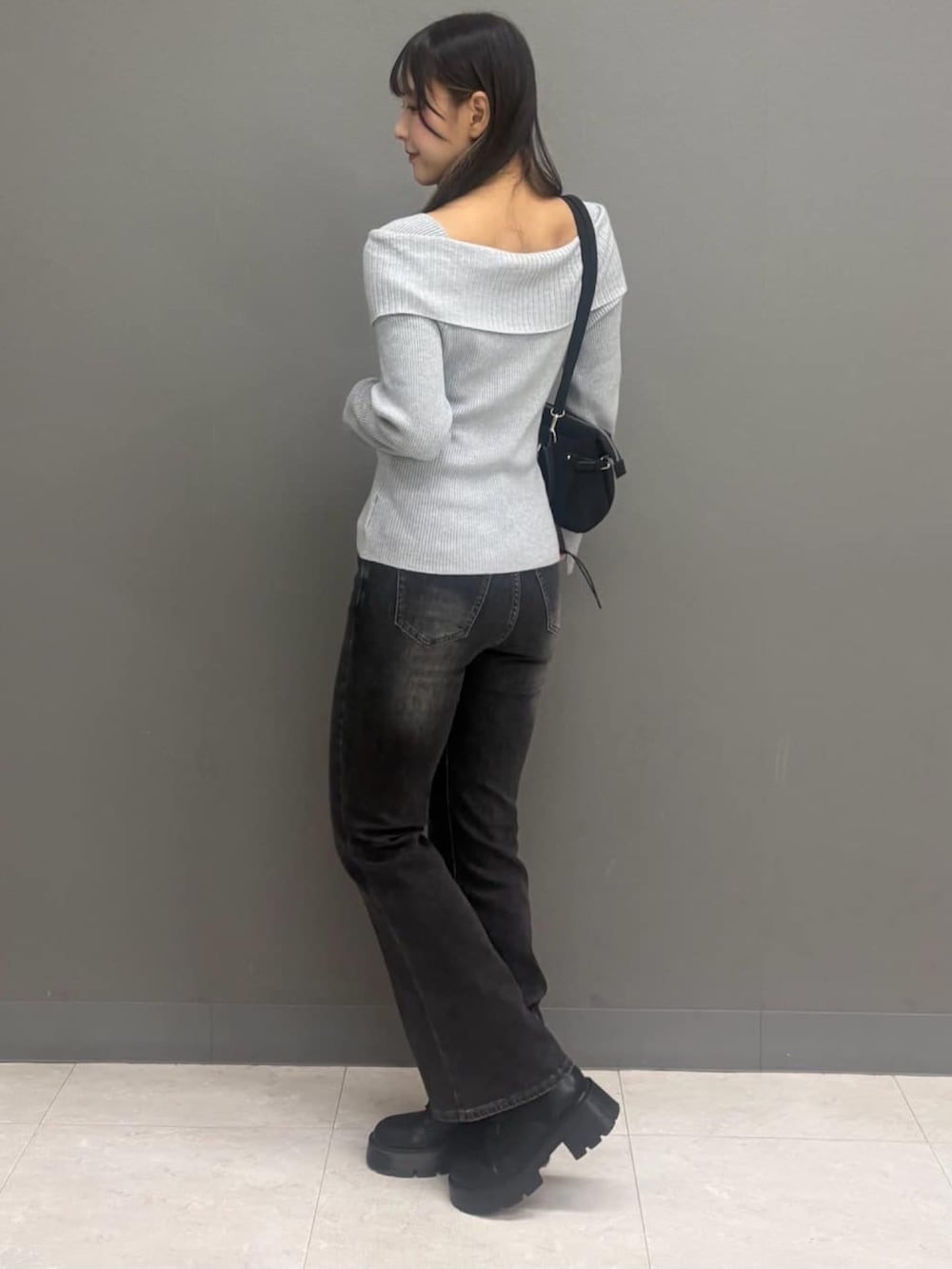 グレー系のデニムパンツ、グレー系のニット/セーター、ブラック系のハンドバッグを着用したレディースの秋コーディネートの3枚目の写真