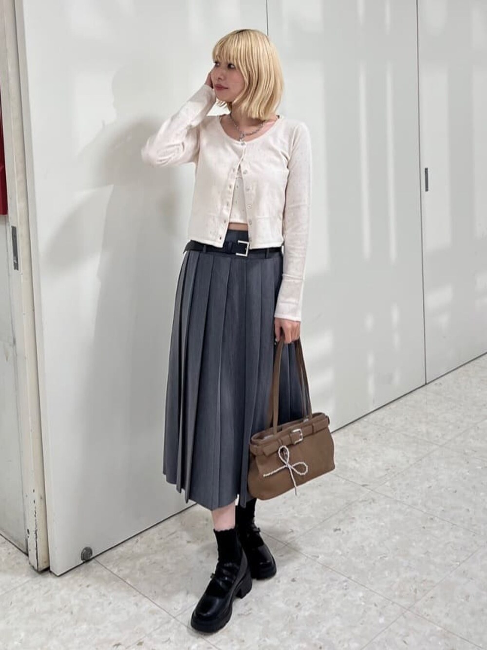 グレー系のスカート、ホワイト系のアンサンブル、ブラウン系のショルダーバッグを着用したレディースの夏コーディネートの3枚目の写真