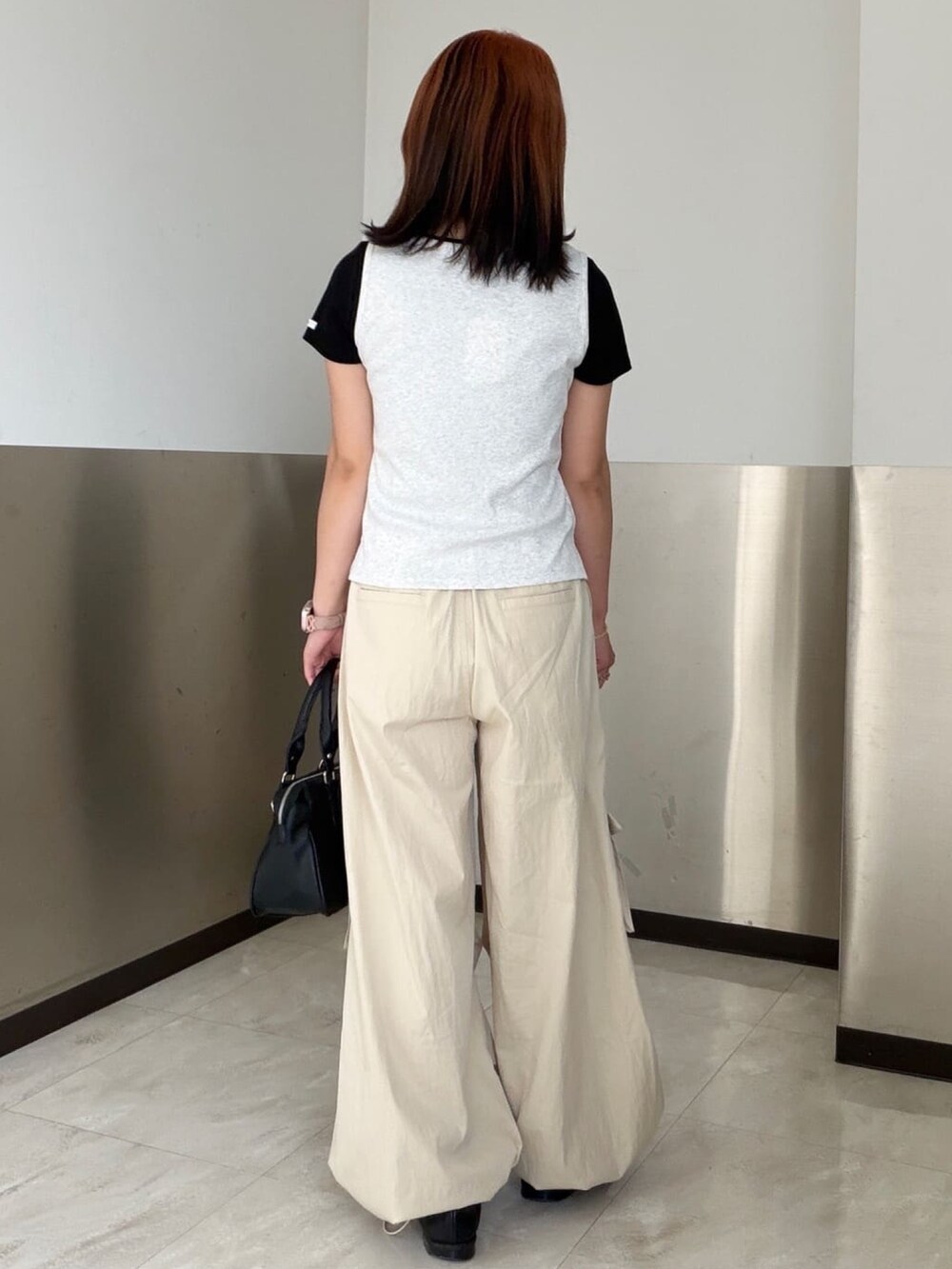 ホワイト系のカーゴパンツ、ブラック系のショルダーバッグ、グレー系のタンクトップを着用したレディースの夏コーディネートの3枚目の写真