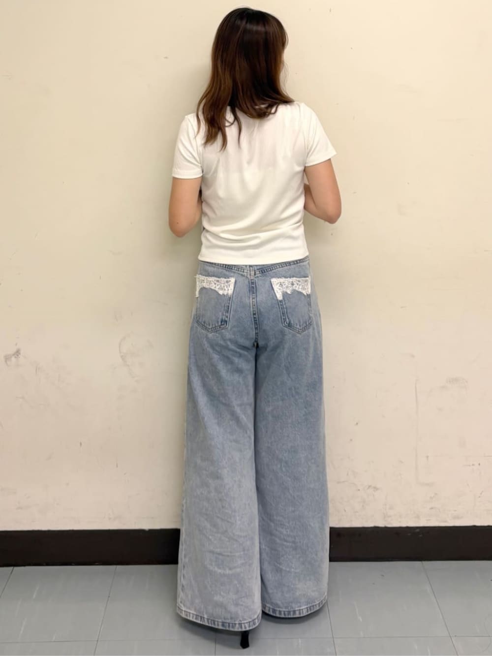 ブルー系のデニムパンツ、ブラック系のサンダル、ホワイト系のTシャツ/カットソーを着用したレディースの夏コーディネートの2枚目の写真