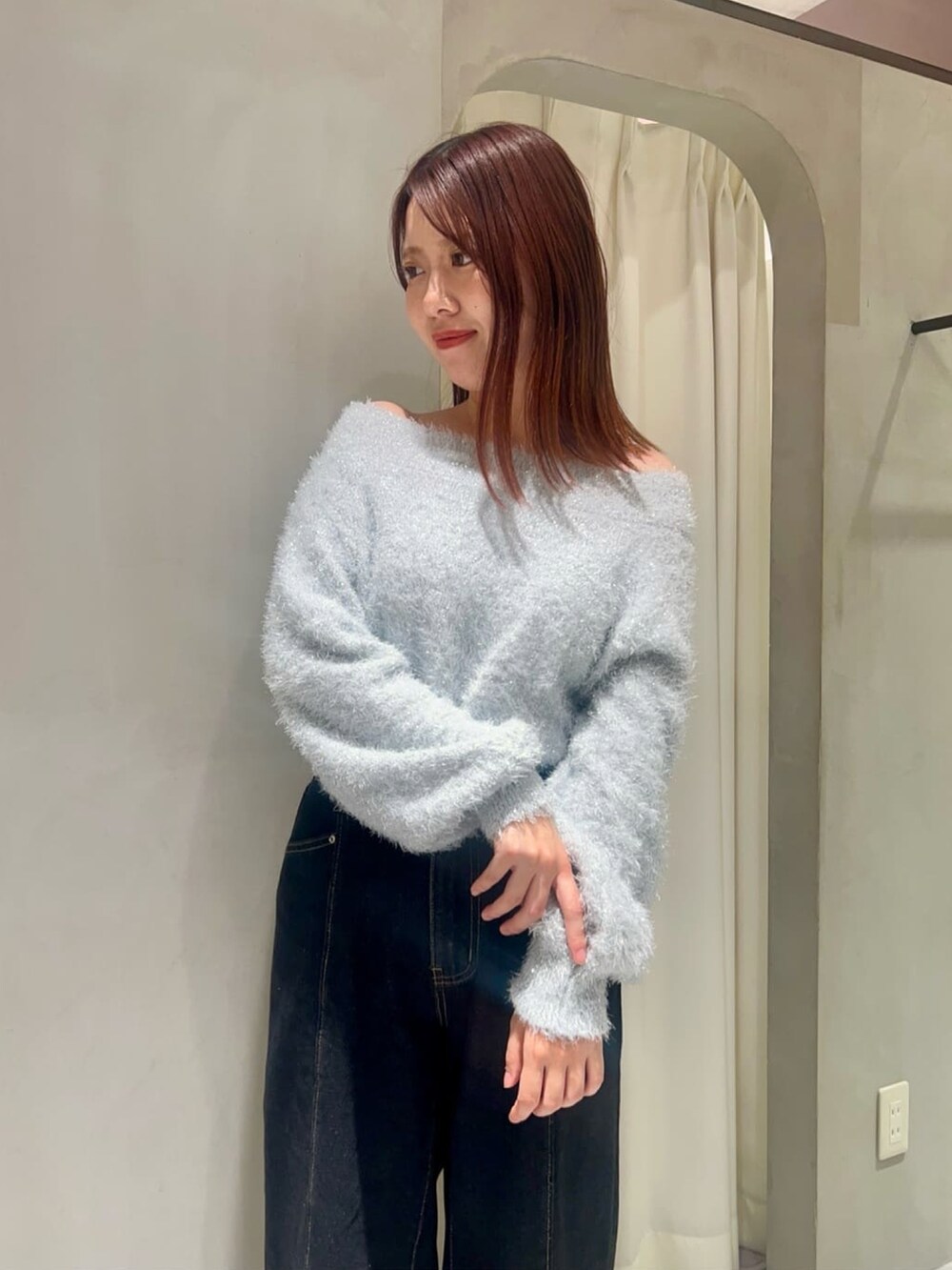 ブラック系のデニムパンツ、ホワイト系のショルダーバッグ、ブルー系のニット/セーターを着用したレディースの冬コーディネートの2枚目の写真