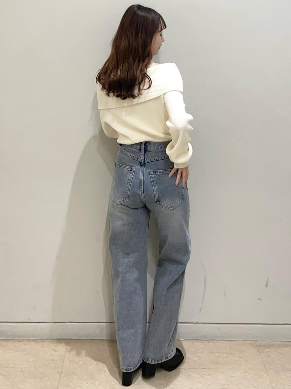 ブルー系のデニムパンツ、ホワイト系のニット/セーター、ブラック系のショルダーバッグを着用したレディースの冬コーディネートの3枚目の写真