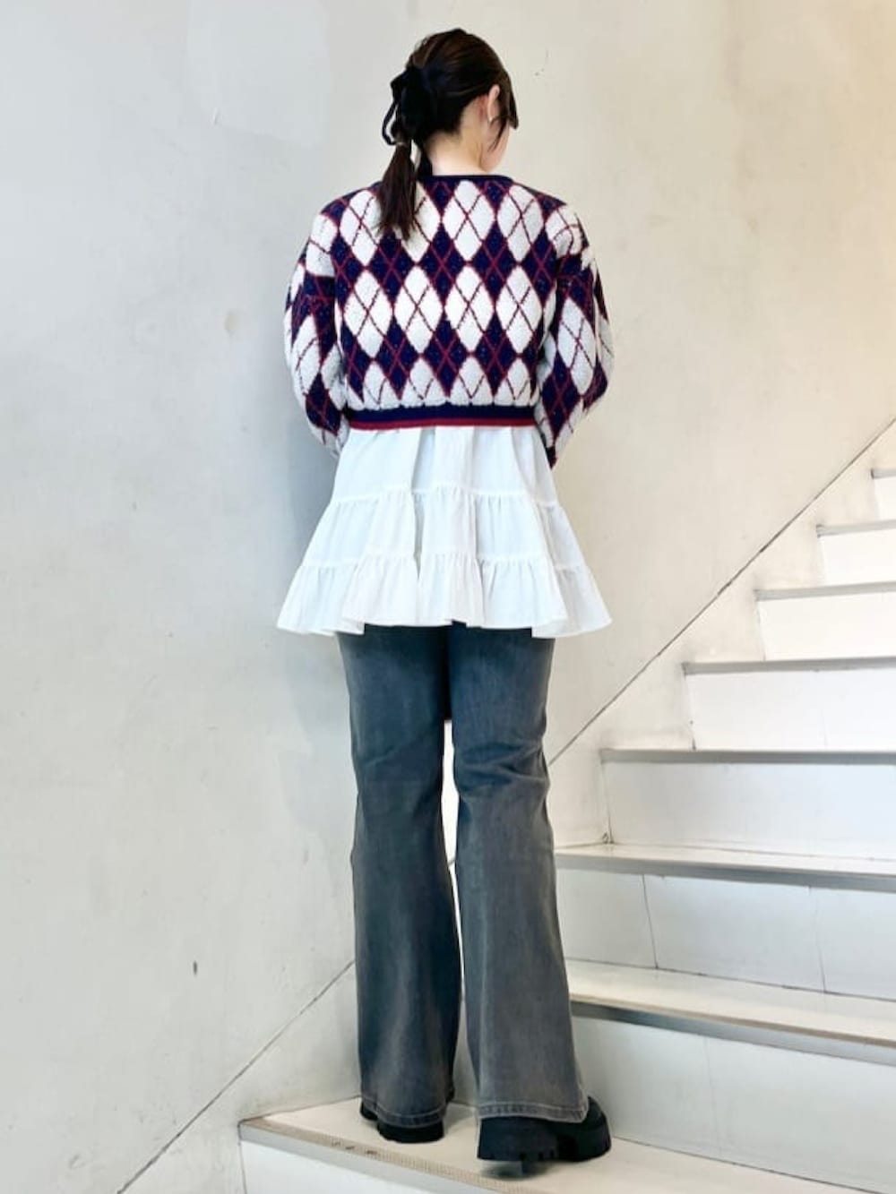 ブルー系のニット/セーター、レッド系のショルダーバッグ、ホワイト系のワンピースを着用したレディースの冬コーディネートの2枚目の写真