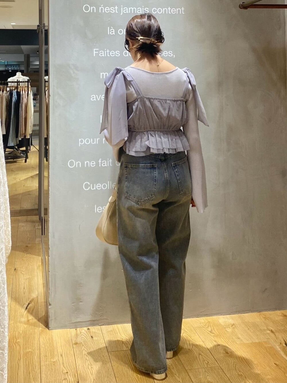 グレー系のアンサンブル、ブルー系のデニムパンツ、ホワイト系のショルダーバッグを着用したレディースの春コーディネートの2枚目の写真