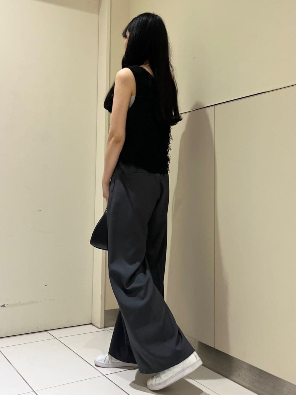 ブラック系のベスト、グレー系のスラックスを着用したレディースの夏コーディネートの3枚目の写真