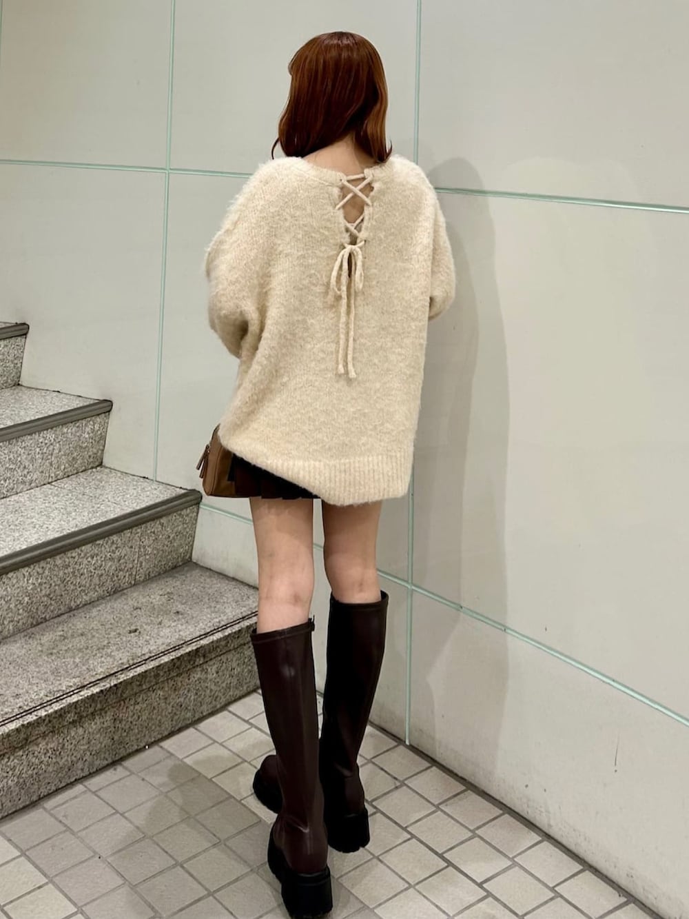 ホワイト系のニット/セーター、ブラウン系のスカート、ブラック系のブーツを着用したレディースの秋コーディネートの2枚目の写真