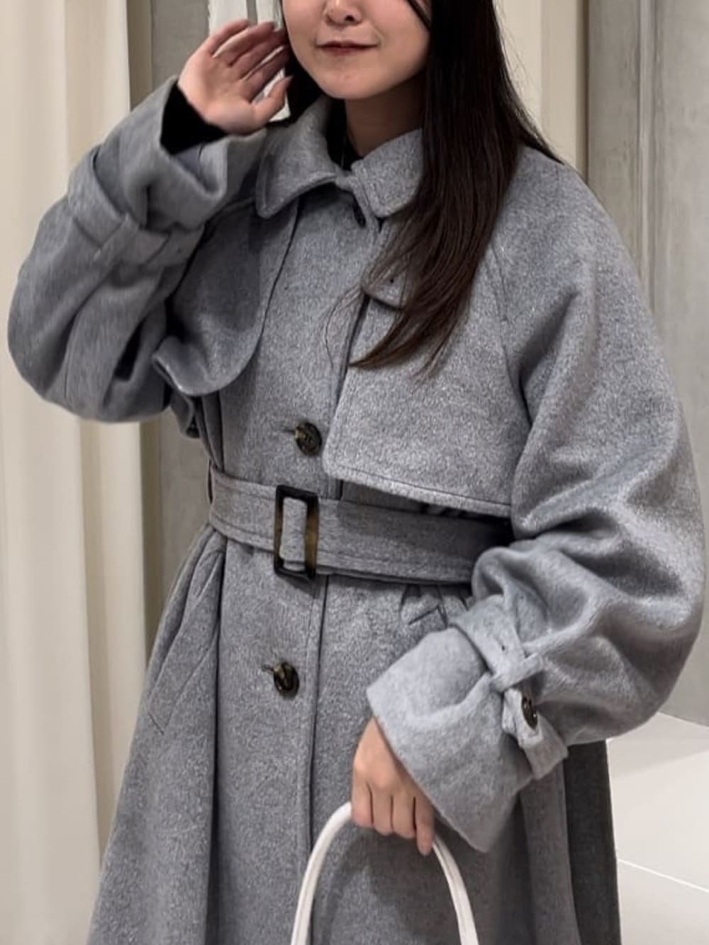 ホワイト系のトレンチコート、ブラウン系のショルダーバッグを着用したレディースの冬コーディネートの3枚目の写真