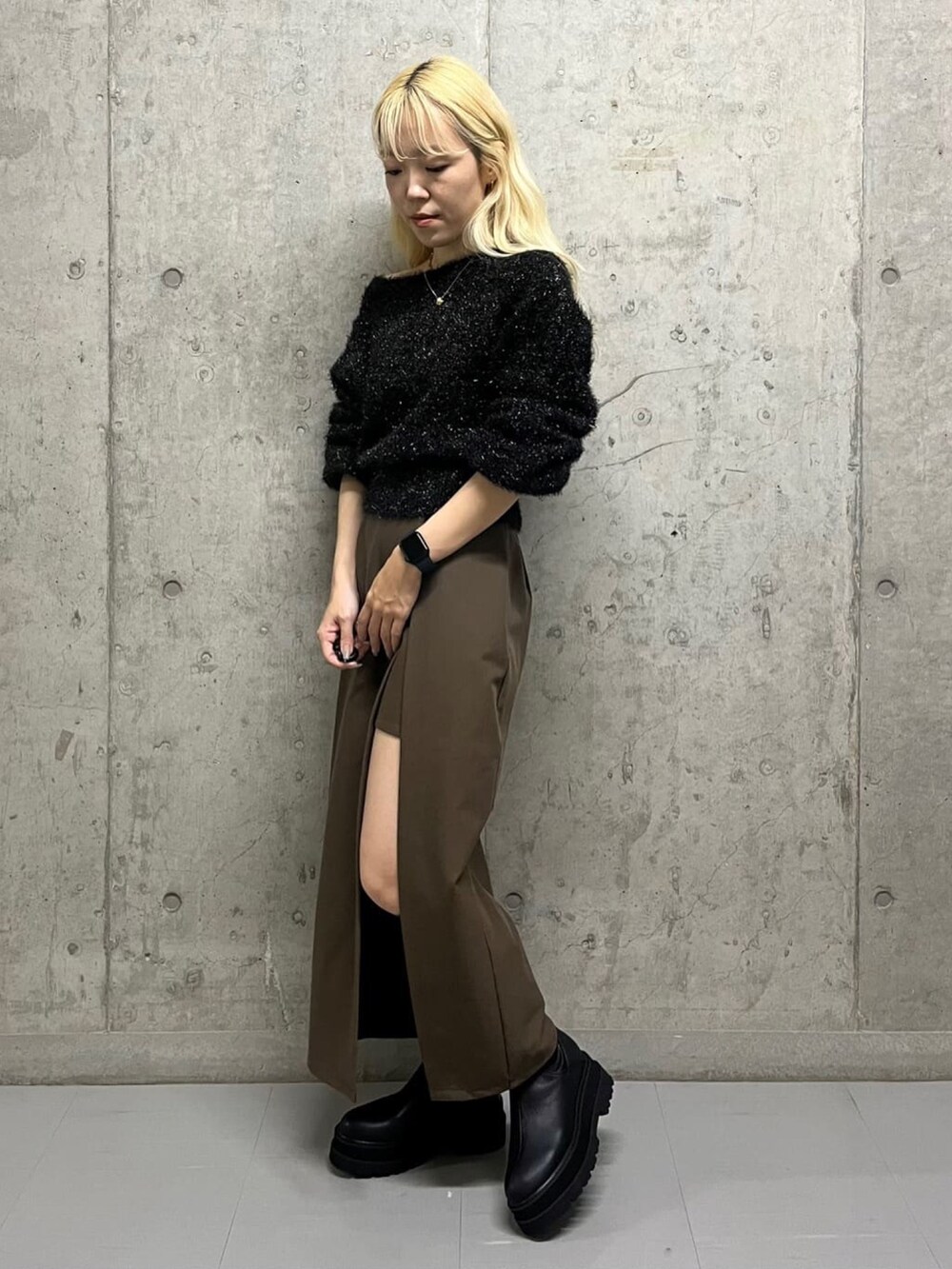 ブラック系のニット/セーター、ブラウン系のスカート、ブラック系のブーツを着用したレディースの冬コーディネートの2枚目の写真