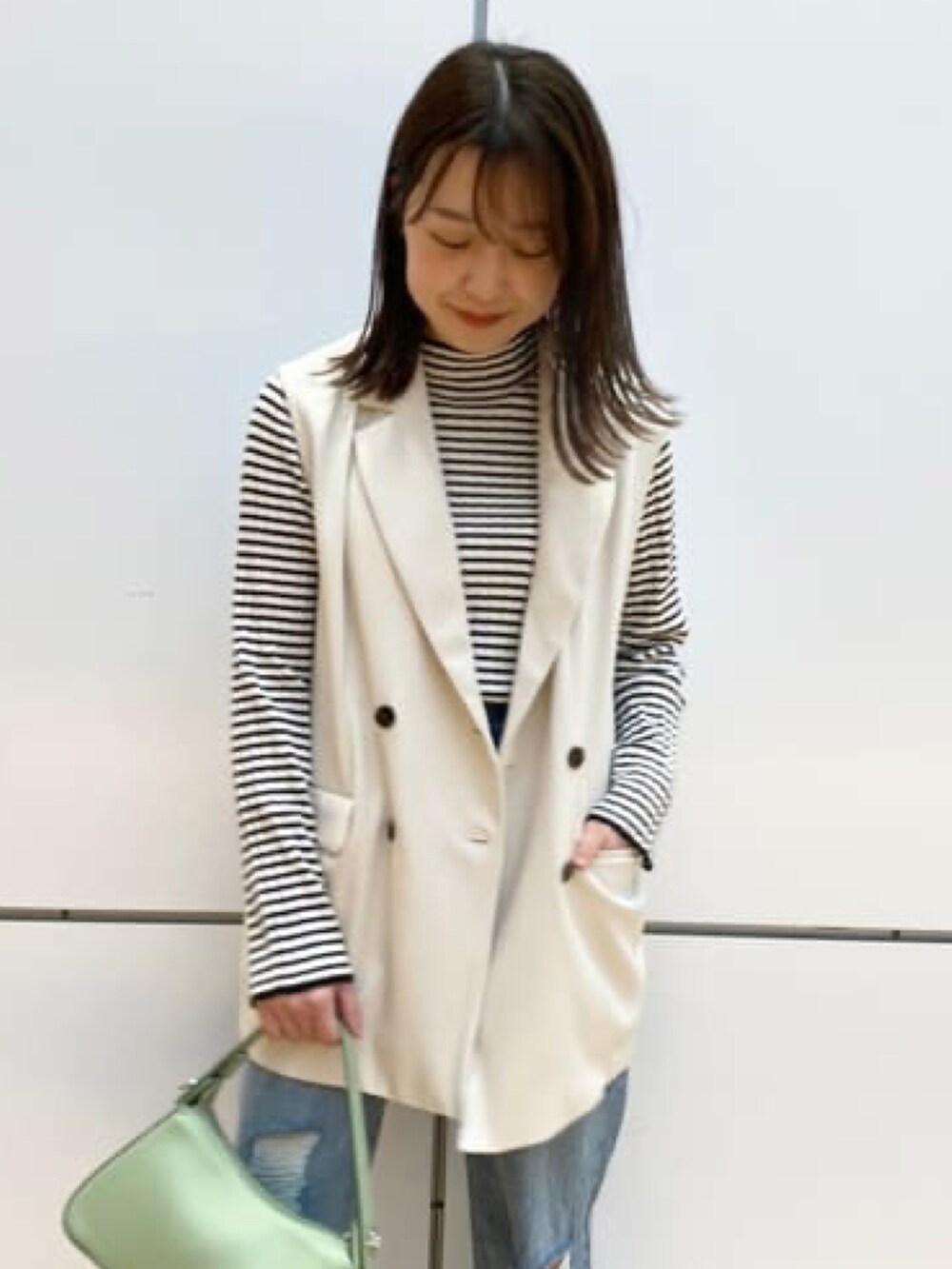 ホワイト系のベスト、ホワイト系のニット/セーター、ブルー系のデニムパンツを着用したレディースの冬コーディネートの2枚目の写真