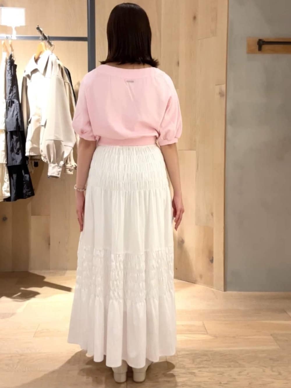 ピンク系のスウェット、ホワイト系のスカート、ホワイト系のパンプスを着用したレディースの春コーディネートの2枚目の写真