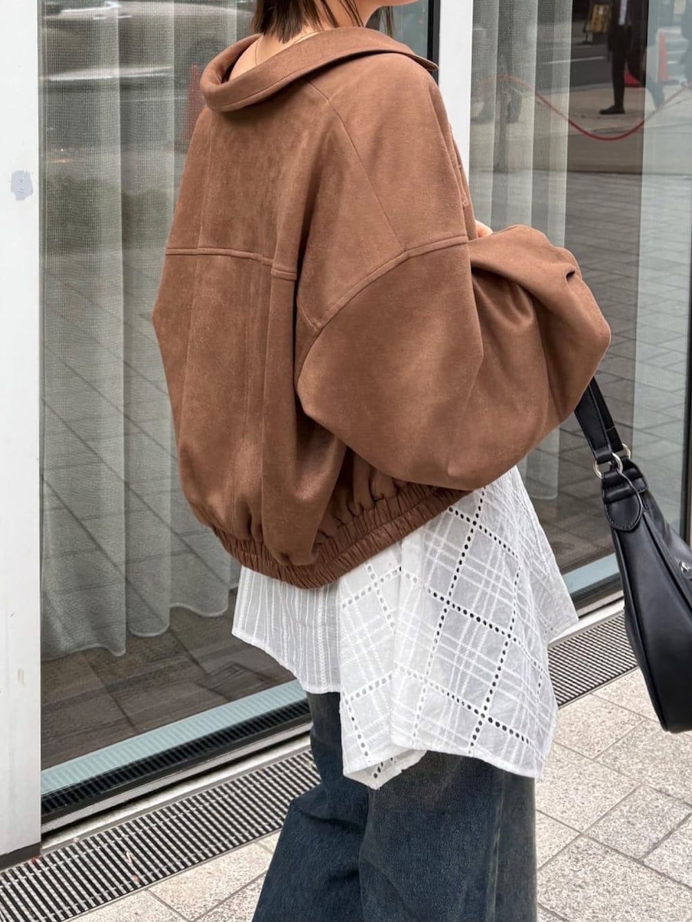 ブラウン系のブルゾン、ホワイト系のワンピース、ブルー系のデニムパンツを着用したレディースの春コーディネートの5枚目の写真