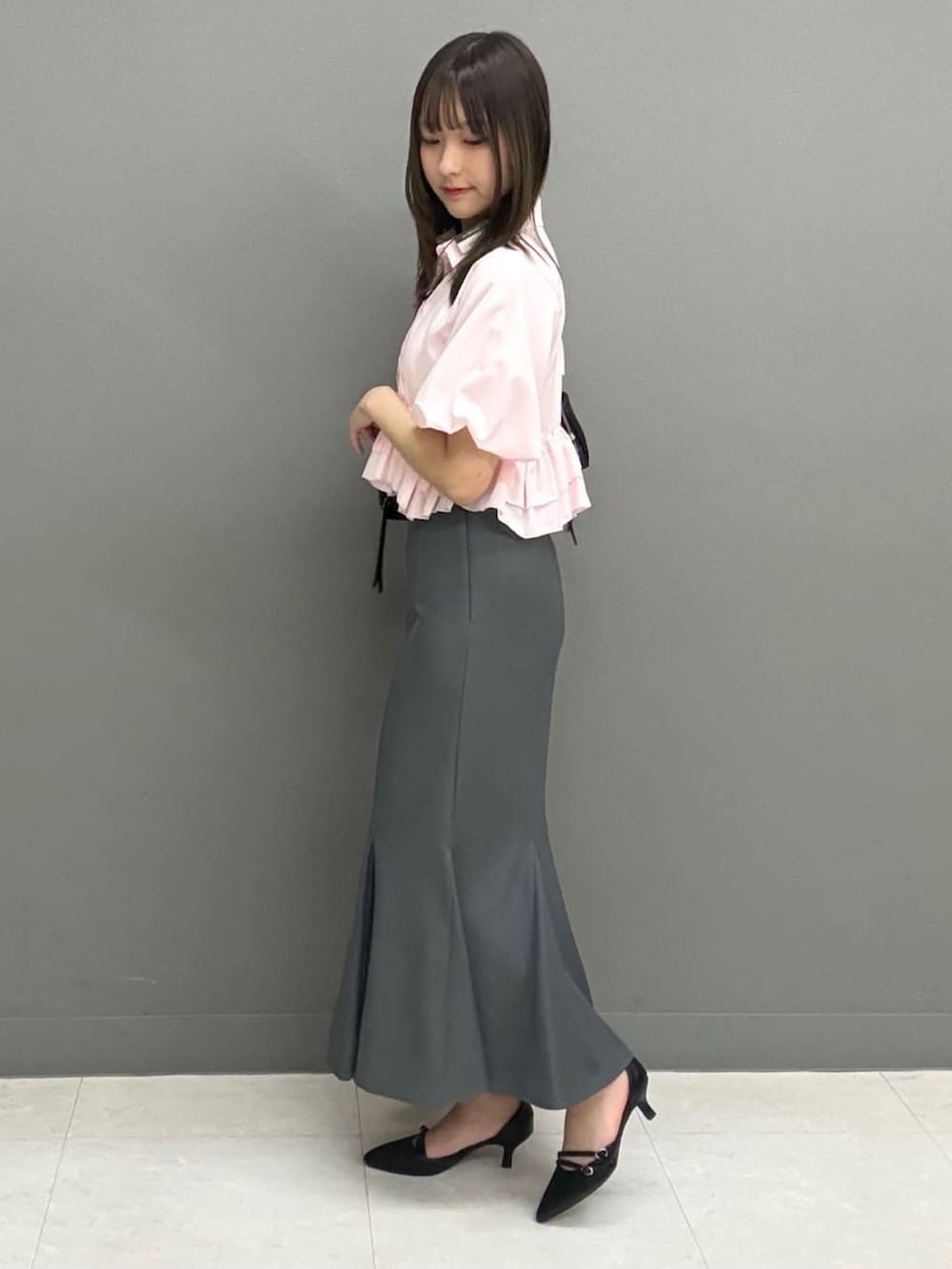 ピンク系のシャツ/ブラウス、グレー系のスカート、ブラック系のボストンバッグを着用したレディースの夏コーディネートの2枚目の写真