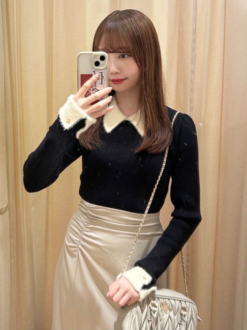 ブラック系のニット/セーター、ホワイト系のスカート、ブラック系のローファーを着用したレディースの冬コーディネートの2枚目の写真