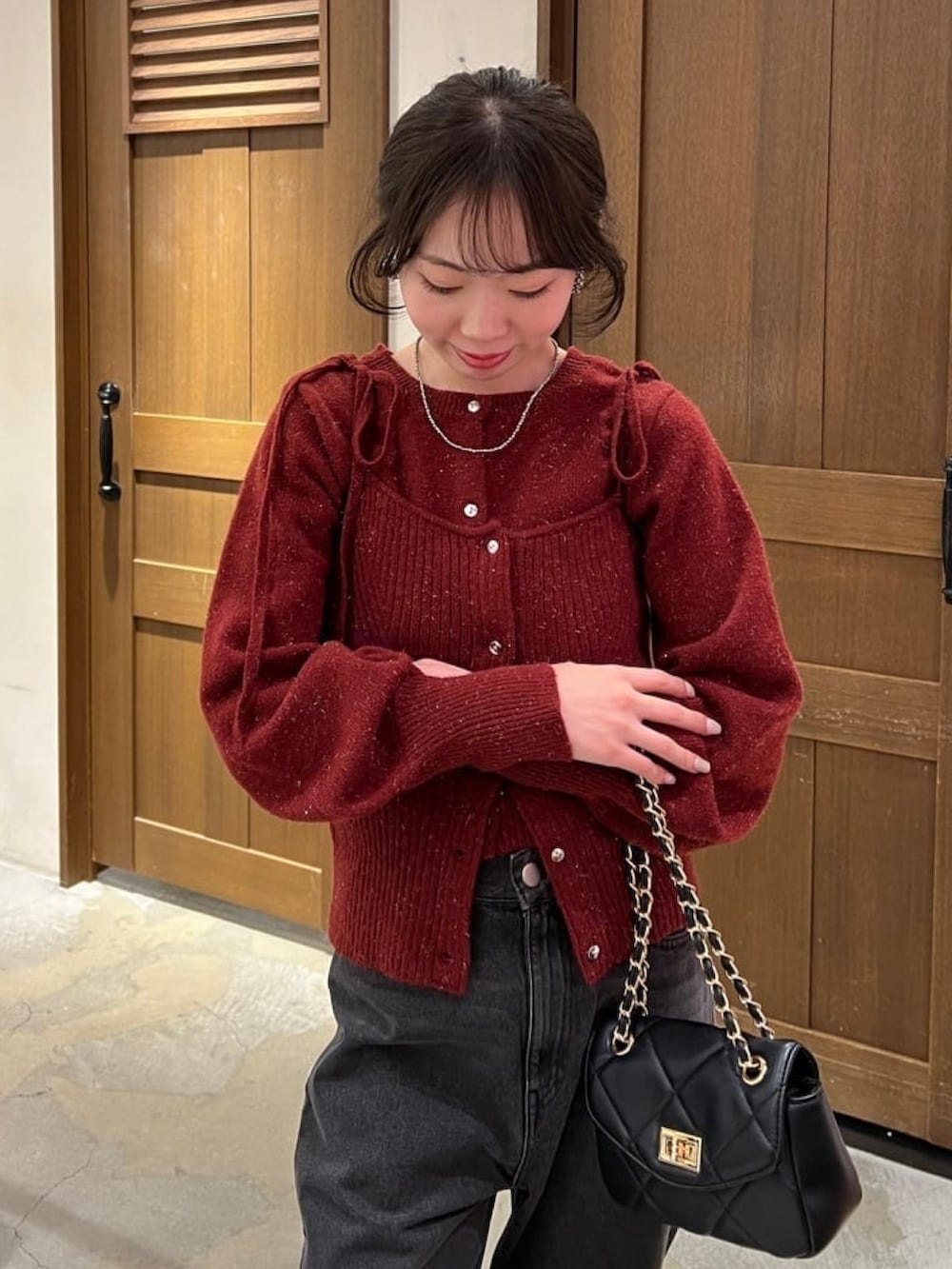 レッド系のニット/セーター、ブラック系のデニムパンツ、ブラック系のショルダーバッグを着用したレディースの冬コーディネートの3枚目の写真