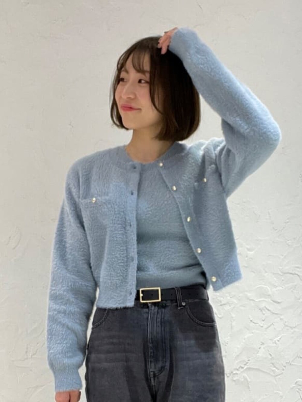 ブルー系のニット/セーター、ブラック系のデニムパンツ、ホワイト系のボストンバッグを着用したレディースの冬コーディネートの2枚目の写真