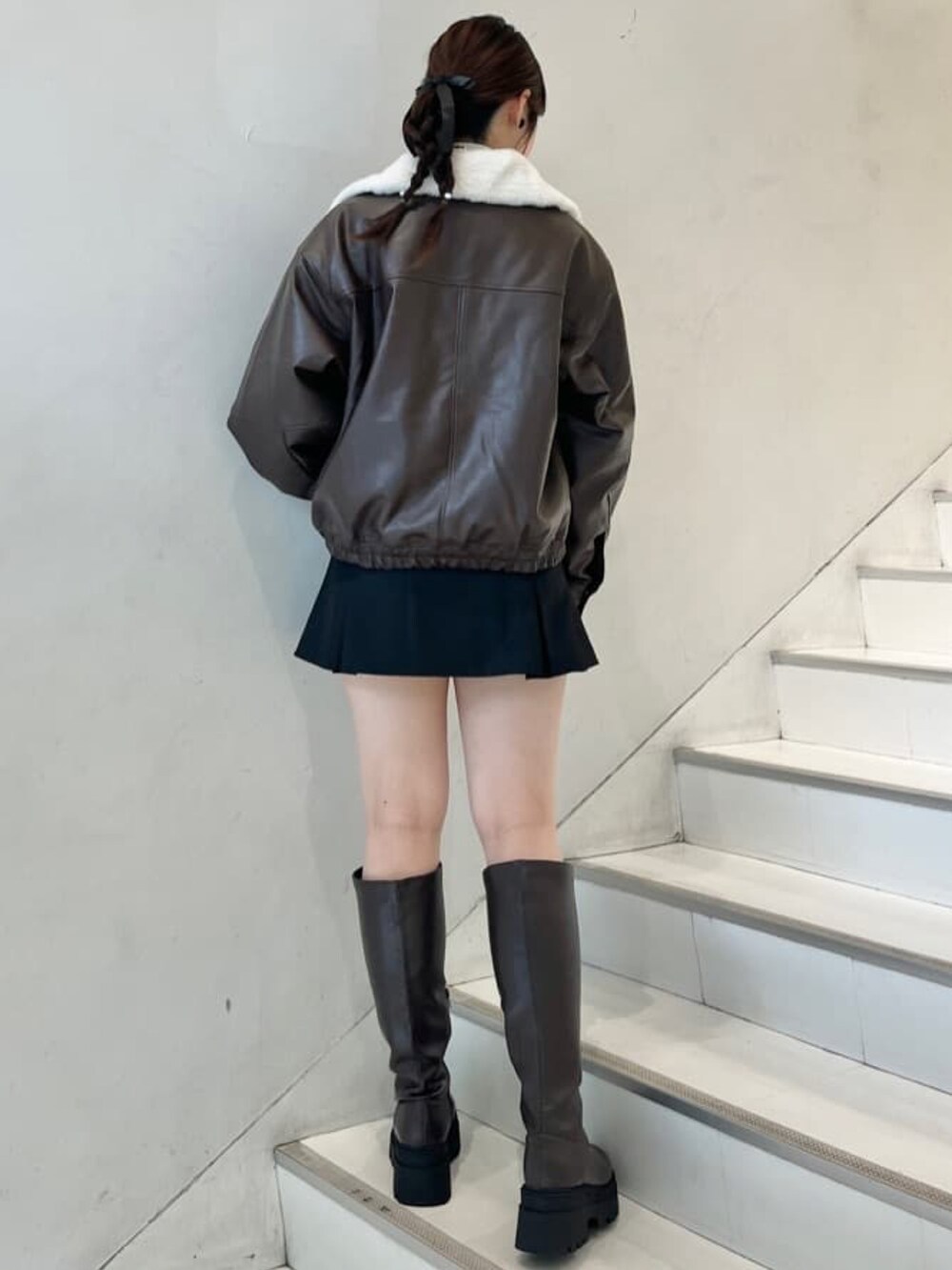 ブラック系のブルゾン、レッド系のニット/セーター、グレー系のスカートを着用したレディースの冬コーディネートの2枚目の写真