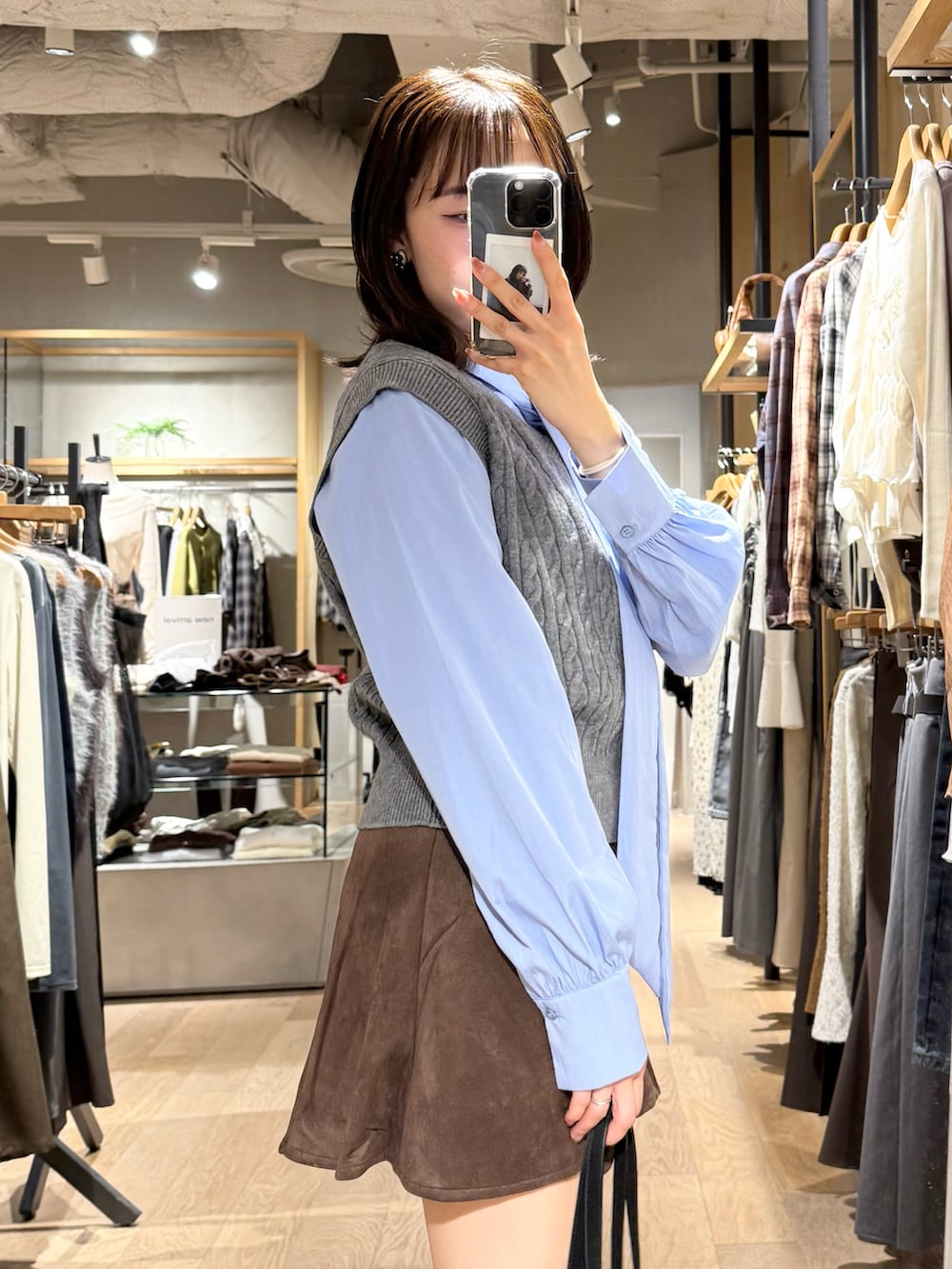 グレー系のニット/セーター、ブラウン系のスカート、ブラック系のショルダーバッグを着用したレディースの秋コーディネートの4枚目の写真