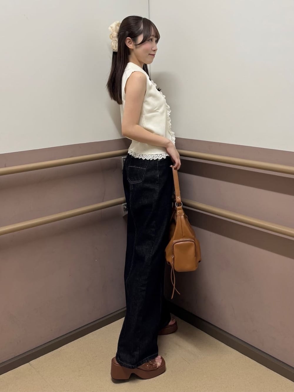 ブラック系のデニムパンツ、ホワイト系のニット/セーター、イエロー系のサンダルを着用したレディースの夏コーディネートの2枚目の写真