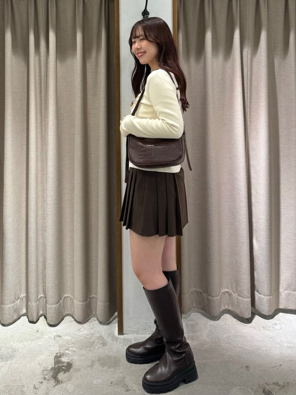 ホワイト系のニット/セーター、ブラウン系のスカートを着用したレディースの冬コーディネートの2枚目の写真