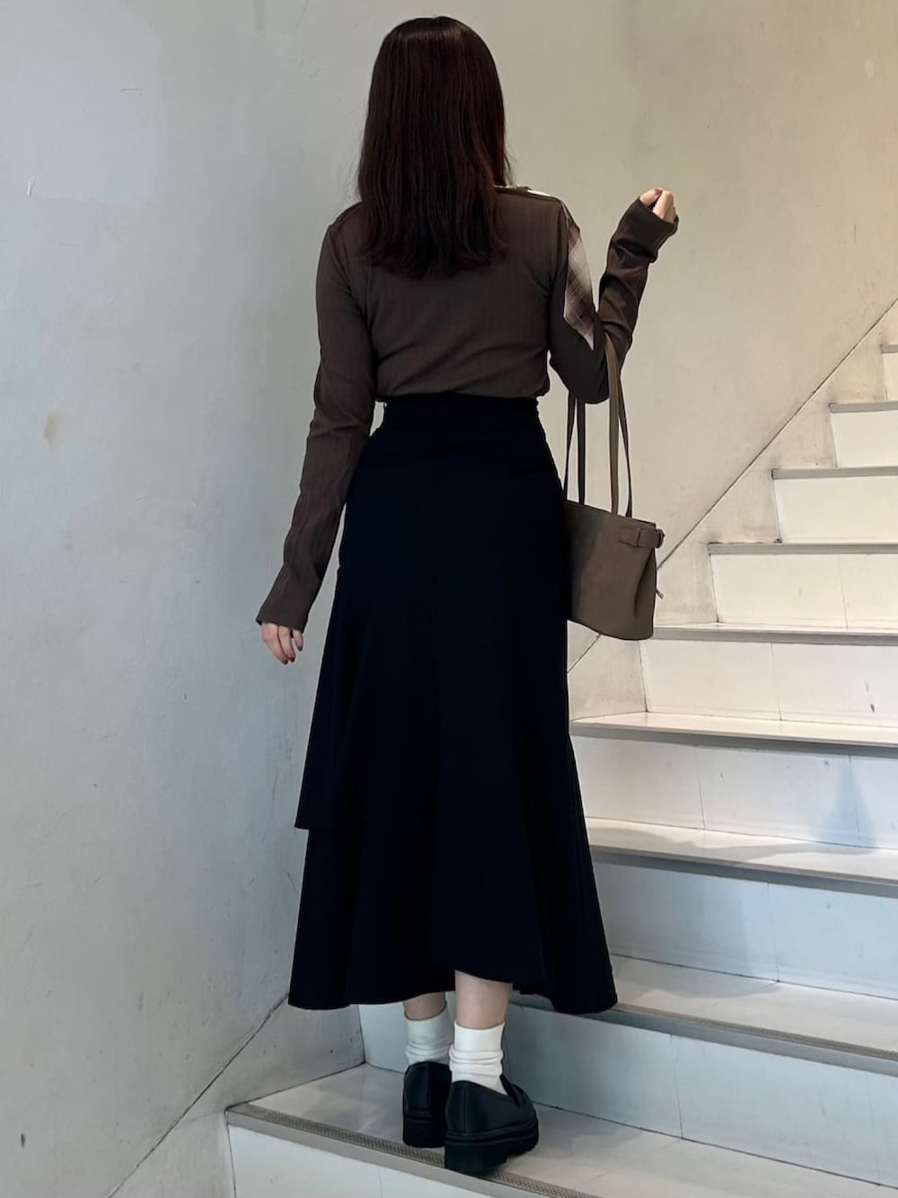 グレー系のTシャツ/カットソー、ブラック系のスカート、ブラウン系のショルダーバッグを着用したレディースの秋コーディネートの2枚目の写真