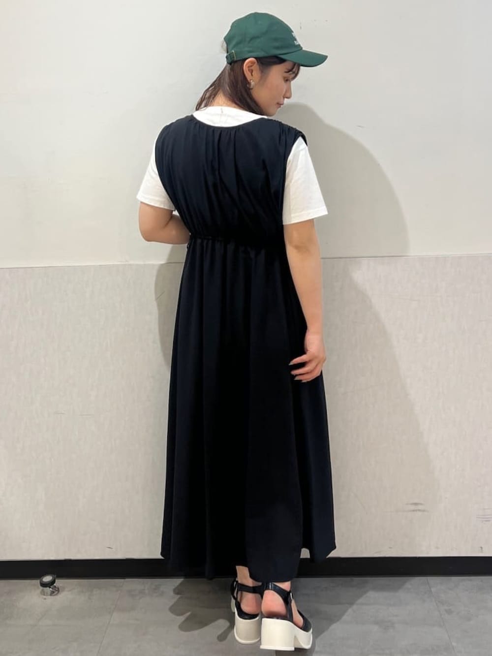 ブラック系のワンピース、ブラック系のサンダル、ホワイト系のTシャツ/カットソーを着用したレディースの夏コーディネートの2枚目の写真