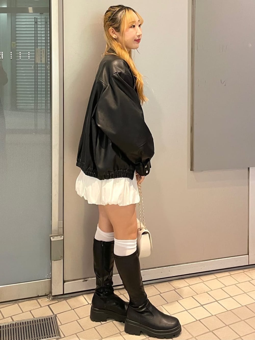 グレー系のニット/セーター、ホワイト系のスカート、ホワイト系のショルダーバッグを着用したレディースの冬コーディネートの2枚目の写真