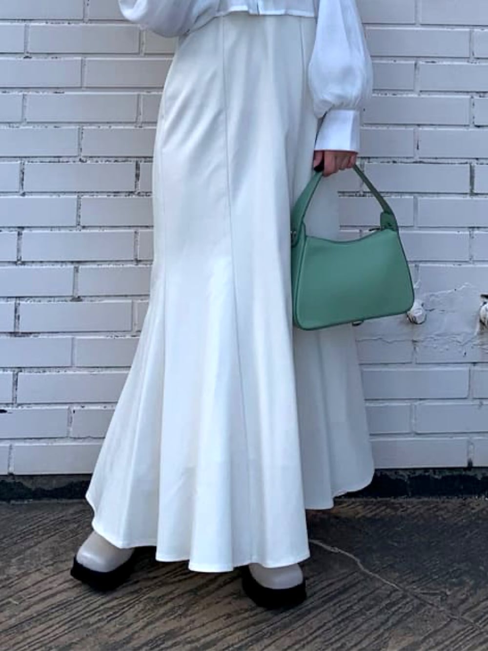 グリーン系のハンドバッグ、ホワイト系のワンピース、ホワイト系のブーツを着用したレディースの冬コーディネートの3枚目の写真