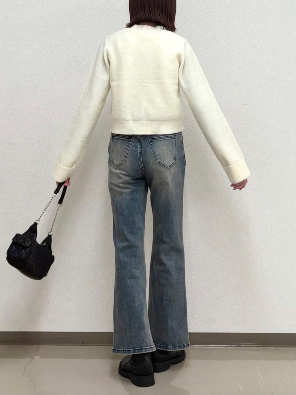 ホワイト系のアンサンブル、ブルー系のデニムパンツを着用したレディースの冬コーディネートの3枚目の写真