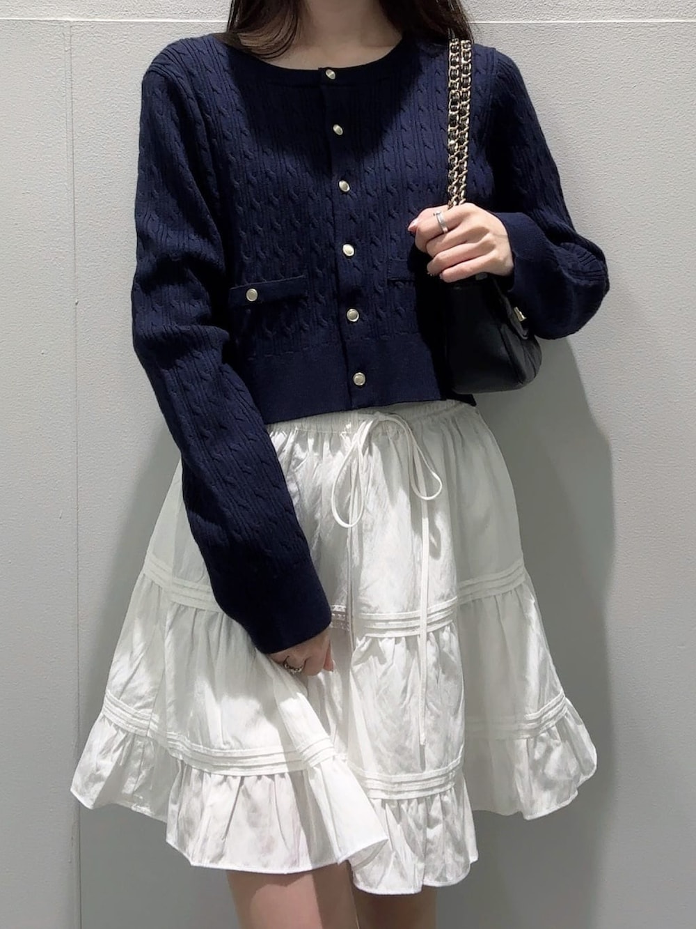 ブルー系のニット/セーター、ブラック系のショルダーバッグ、ホワイト系のスカートを着用したレディースの冬コーディネートの3枚目の写真