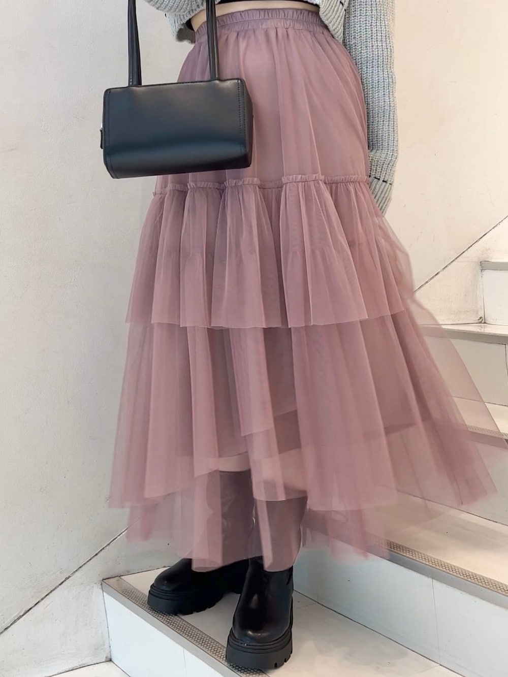 ブラック系のショルダーバッグ、グレー系のニット/セーター、ピンク系のスカートを着用したレディースの冬コーディネートの2枚目の写真