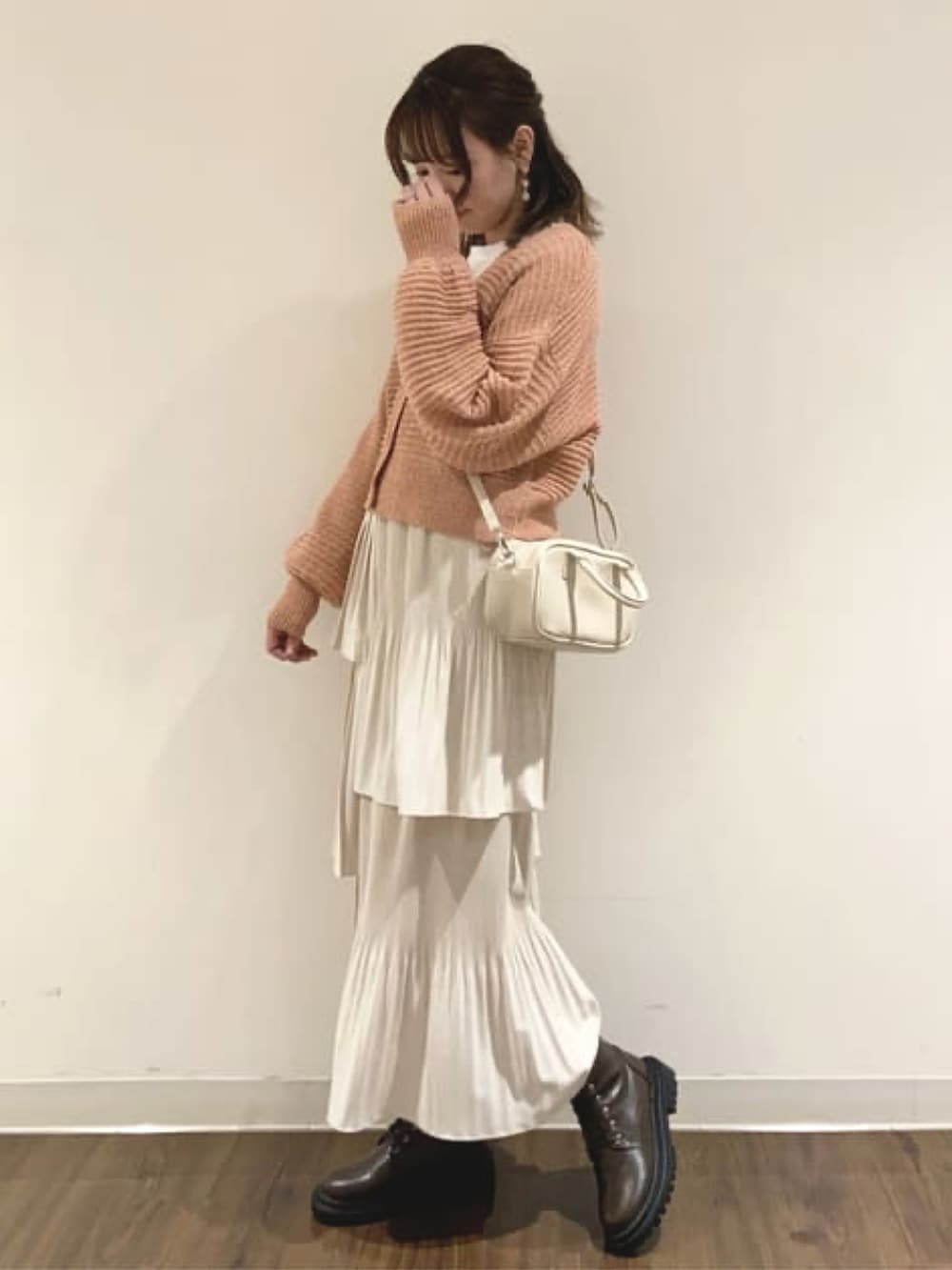 オレンジ系のカーディガン/ボレロ、ホワイト系のスカートを着用したレディースの冬コーディネートの2枚目の写真