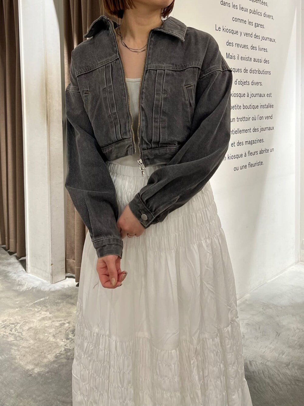 グレー系のブルゾン、ホワイト系のスカートを着用したレディースの春コーディネートの3枚目の写真