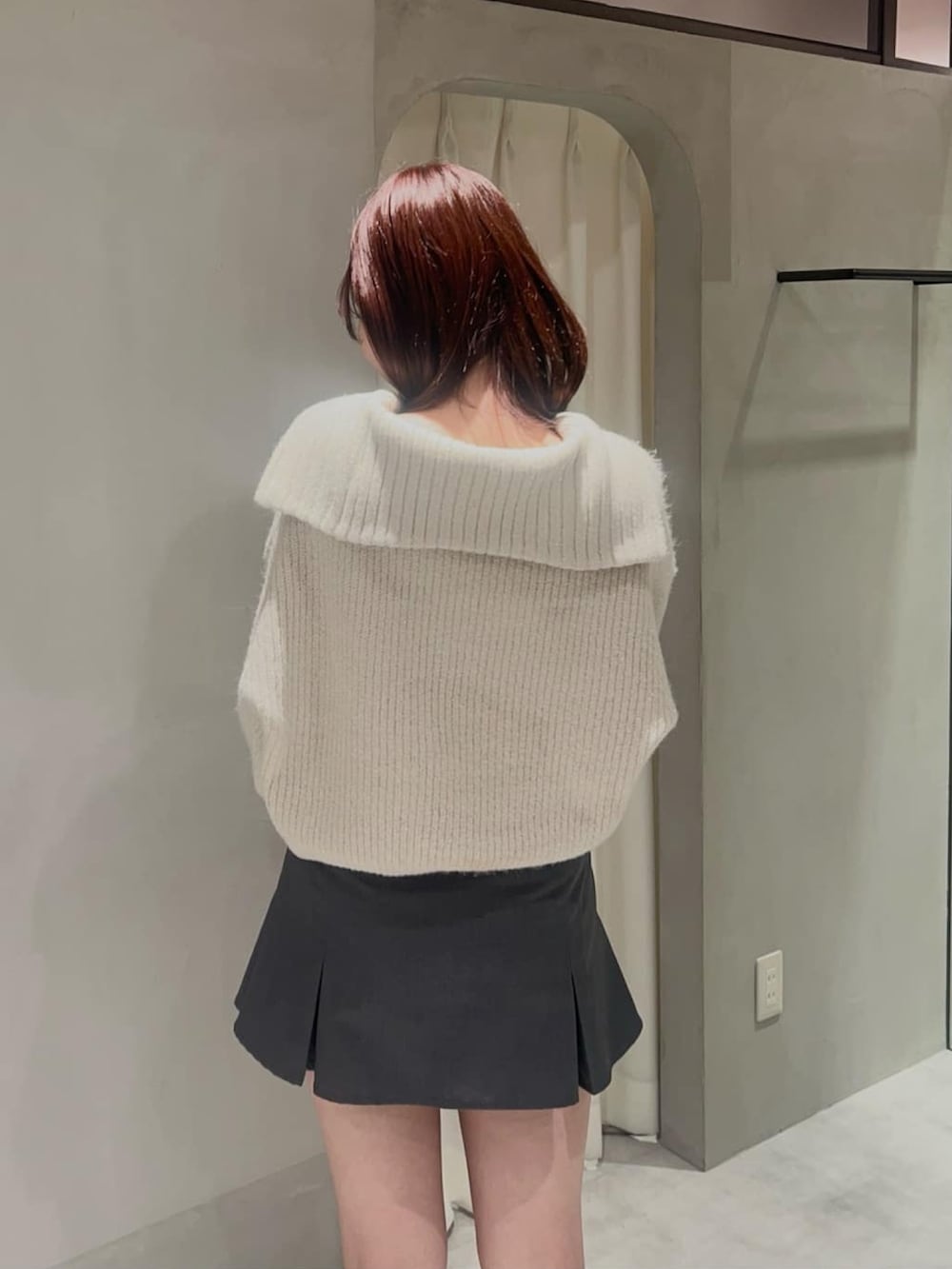 ホワイト系のニット/セーター、グレー系のスカート、ブラウン系のショルダーバッグを着用したレディースの冬コーディネートの2枚目の写真