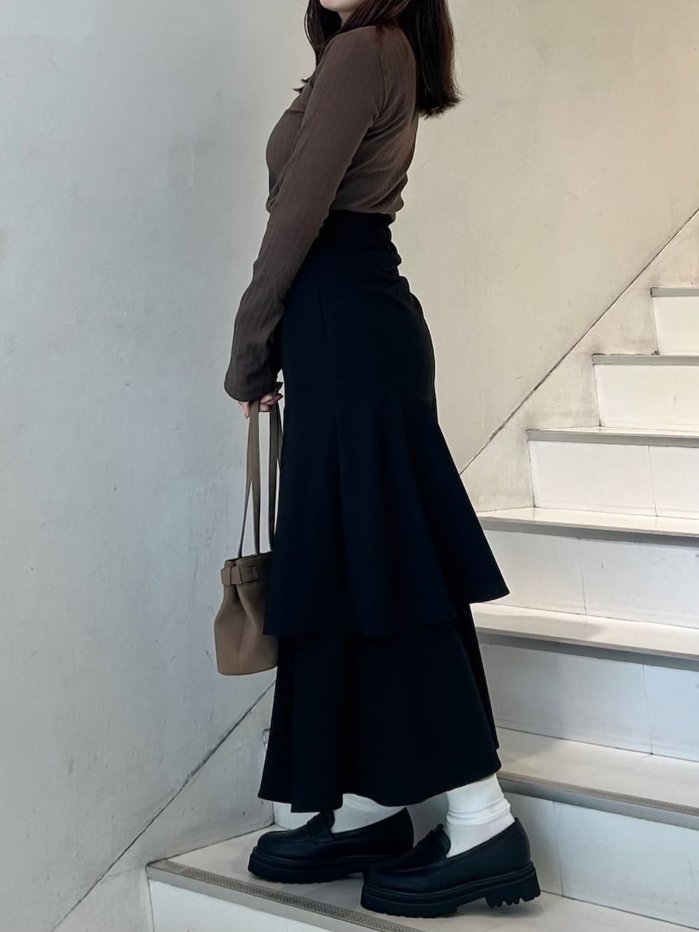 グレー系のTシャツ/カットソー、ブラック系のスカート、ブラウン系のショルダーバッグを着用したレディースの秋コーディネートの3枚目の写真