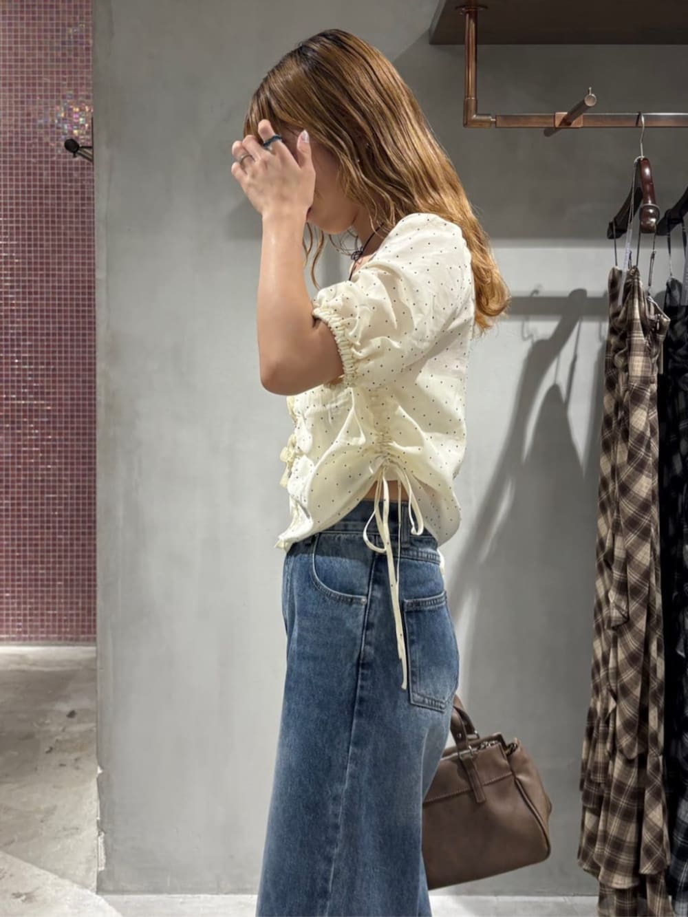 ブルー系のデニムパンツ、ホワイト系のシャツ/ブラウス、ブラウン系のショルダーバッグを着用したレディースの夏コーディネートの3枚目の写真