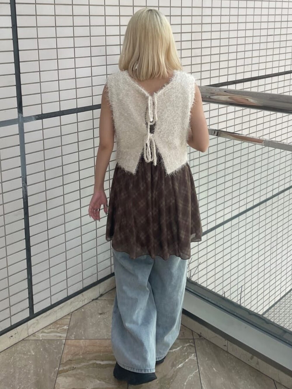 ホワイト系のベスト、ブルー系のデニムパンツ、ブラウン系のワンピースを着用したレディースの夏コーディネートの2枚目の写真