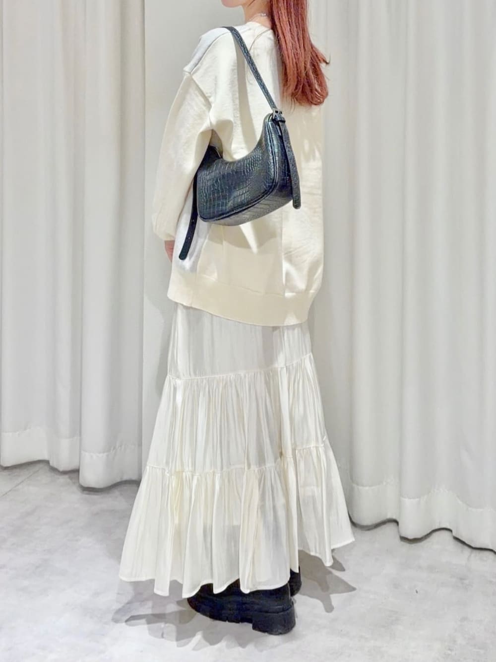 グレー系のニット/セーター、ホワイト系のスカートを着用したレディースの秋コーディネートの2枚目の写真