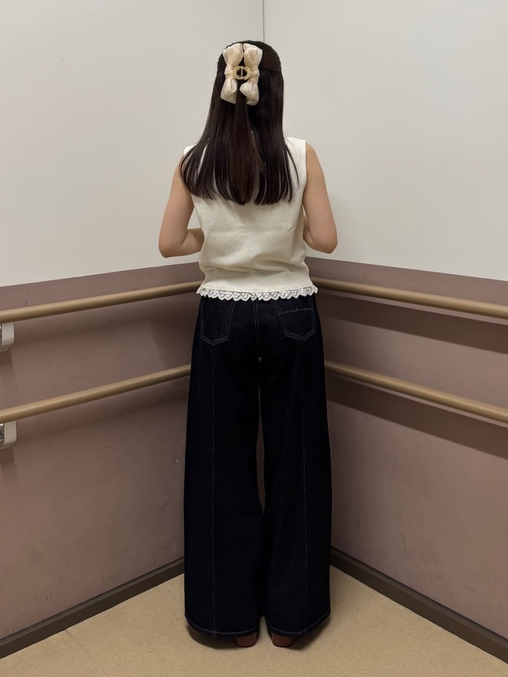ブラック系のデニムパンツ、ホワイト系のニット/セーター、イエロー系のサンダルを着用したレディースの夏コーディネートの3枚目の写真