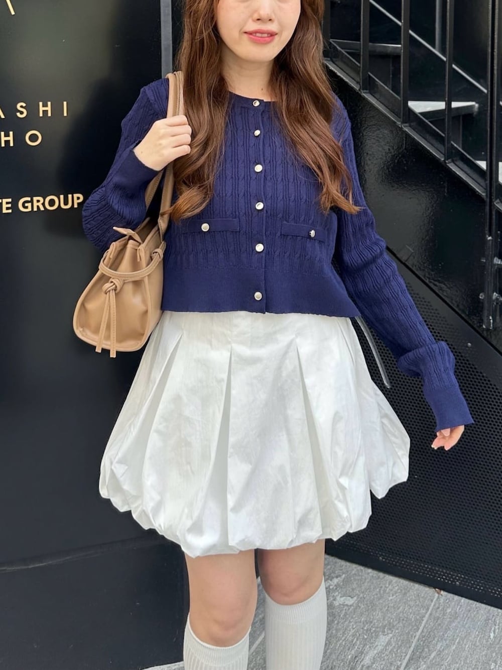 ブルー系のカーディガン/ボレロ、ホワイト系のスカート、ベージュ系のハンドバッグを着用したレディースの春コーディネートの2枚目の写真