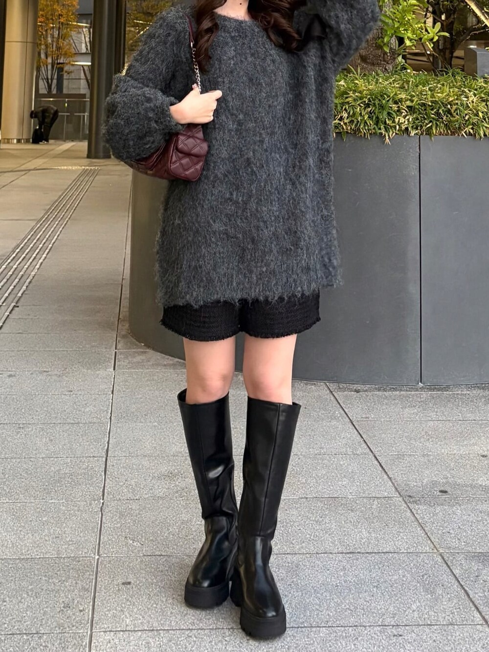 グレー系のチュニック、レッド系のショルダーバッグ、ブラック系のその他パンツを着用したレディースの冬コーディネートの2枚目の写真