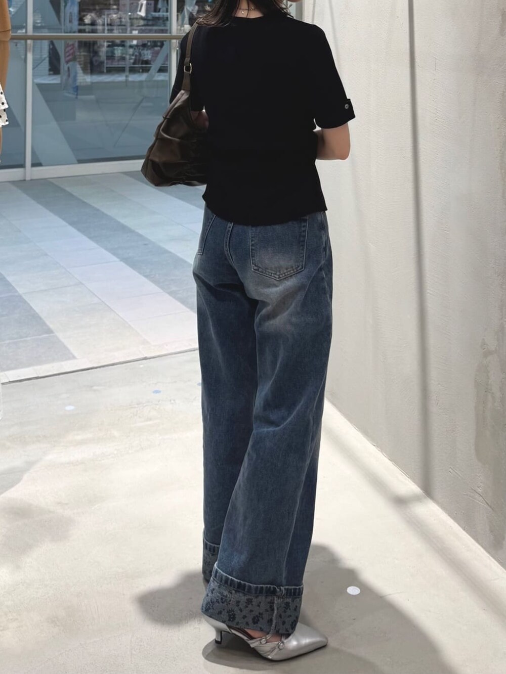 ブルー系のデニムパンツ、ブラック系のニット/セーター、グレー系のパンプスを着用したレディースの夏コーディネートの3枚目の写真