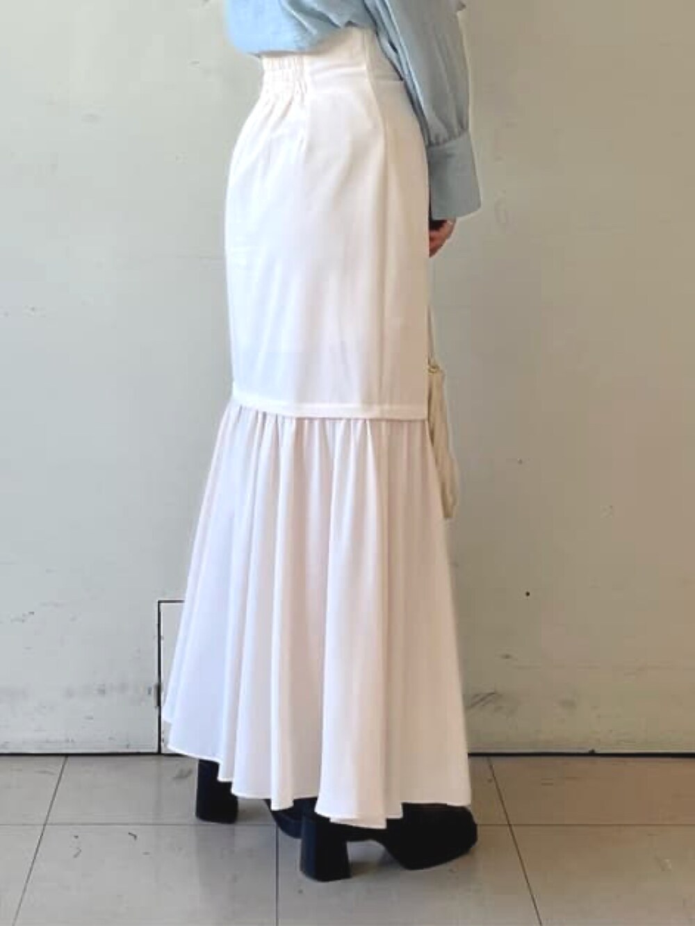 ブルー系のシャツ/ブラウス、ホワイト系のスカート、ホワイト系のハンドバッグを着用したレディースの冬コーディネートの3枚目の写真